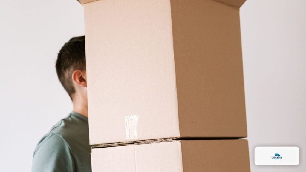 Homme portant seul une pile de cartons de déménagement